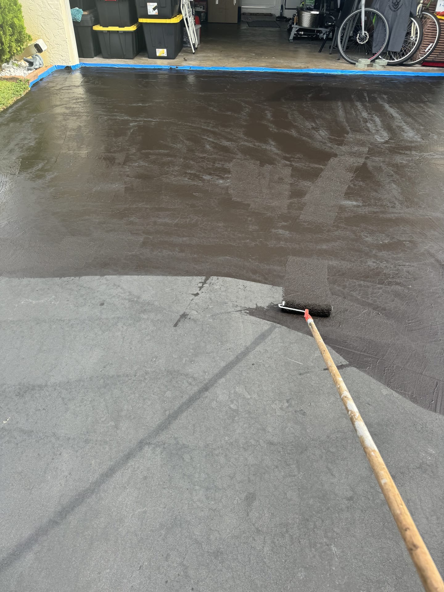 Rolling a sealer onto a cleaned concrete driveway